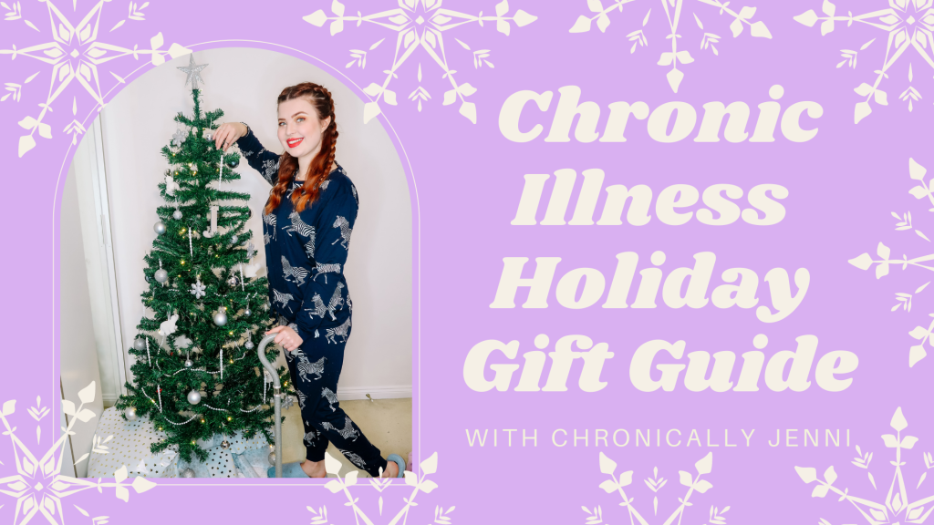 Jenni with long plaited red hair, wearing zebra pajamas, smiling at the camera. She is leaning against her spoonie holiday christmas tree, and her walking stick is visible.