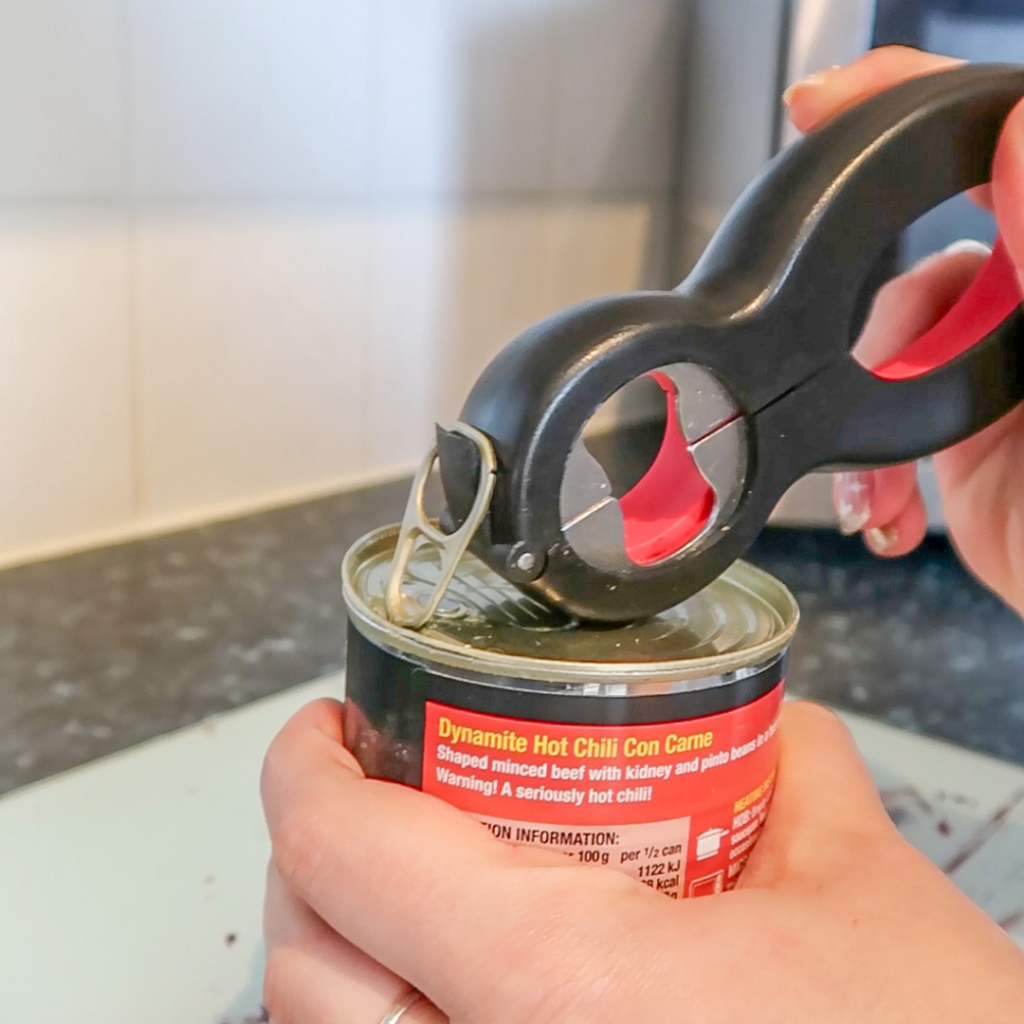 A hand using a 6-in 1 tool on a tin