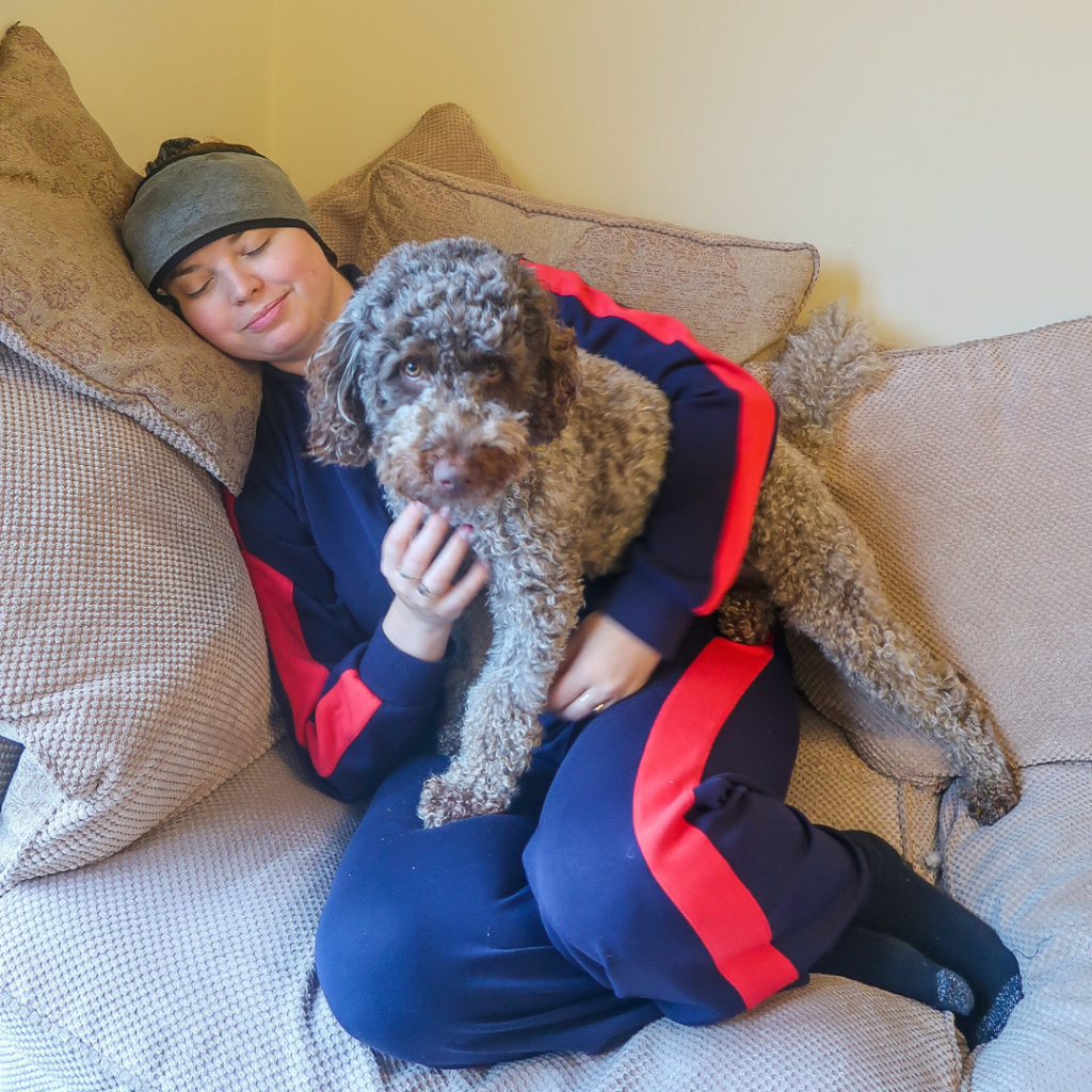 Jenni laid on the sofa, with a head wrap on. Coco sits on her lap.