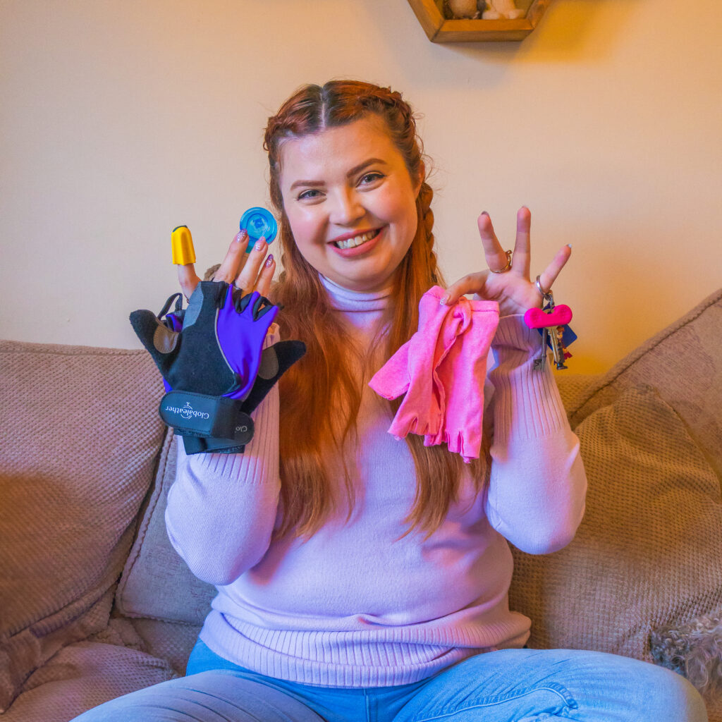 Jenni sat on her sofa, holding up various gloves and hand hack tools