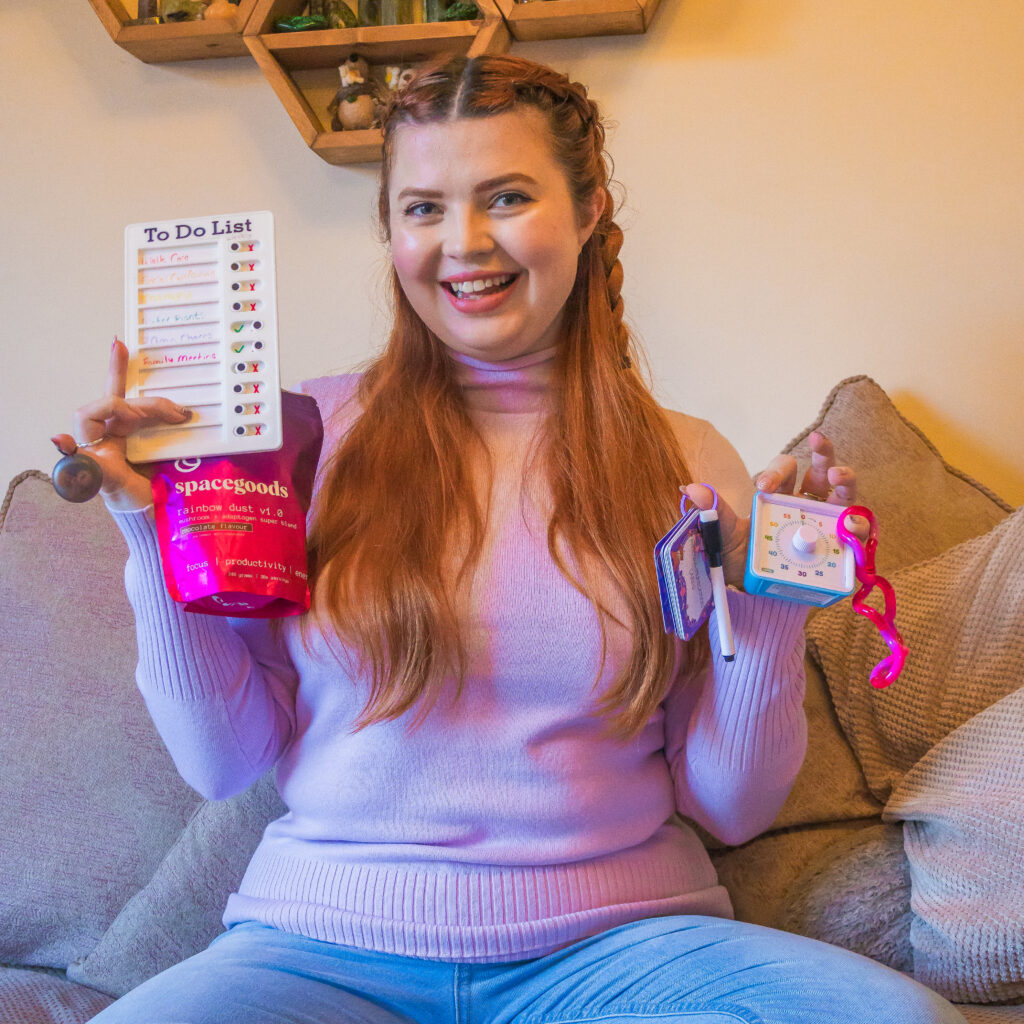 Jenni sat on her sofa holding various ADHD hack tools
