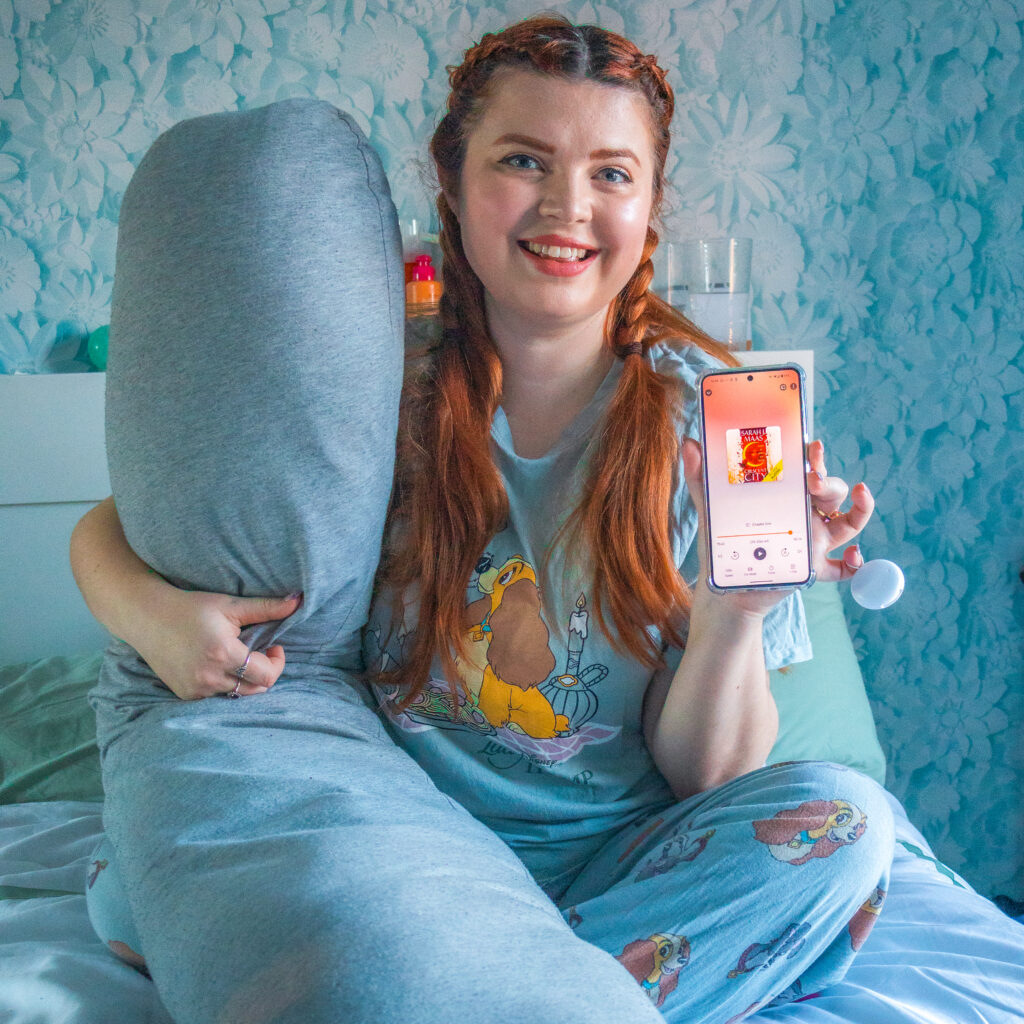 Jenni sat on her bed with a body pillow and her phone, smiling.