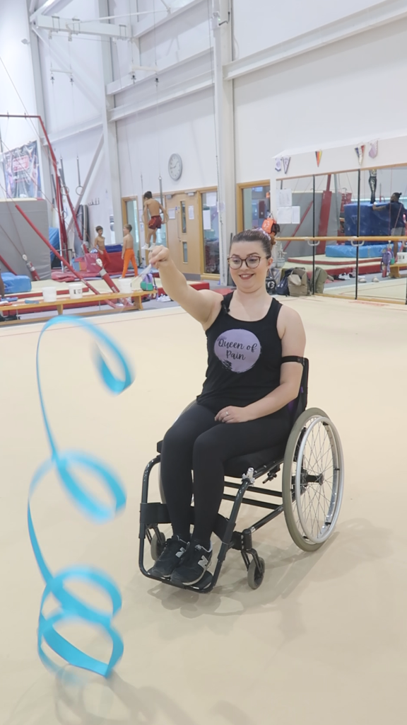Jenni using an gymnastic ribbon from her wheelchair.